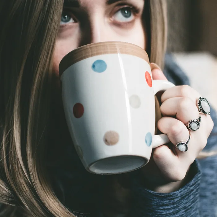Woman holding a warm mug with both hands, looking out thoughtfully