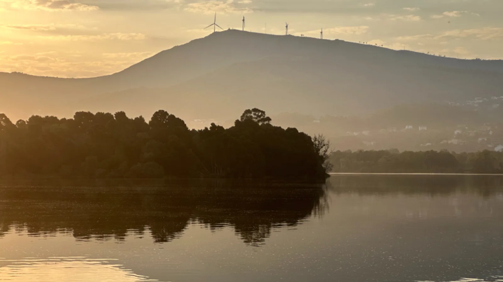 Still lake at sunrise with mist over the hills